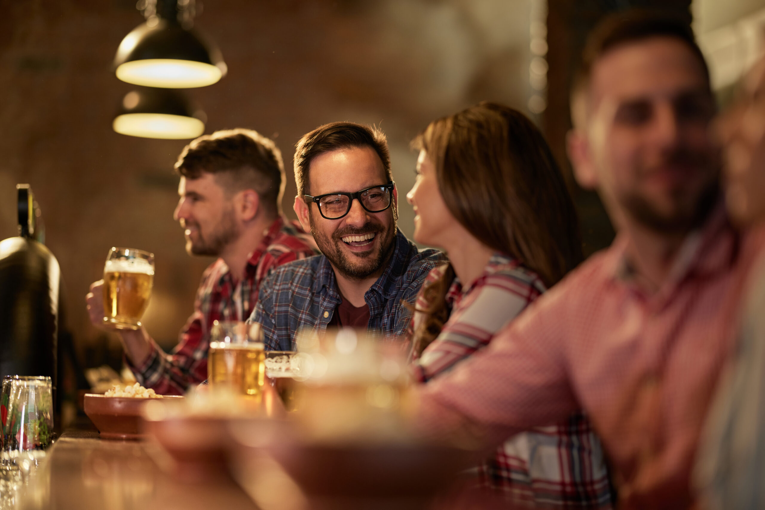 Young happy couple talking while drinking beer in a pub