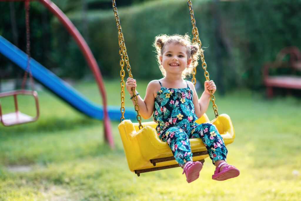 Happy little girl on a swing in the park