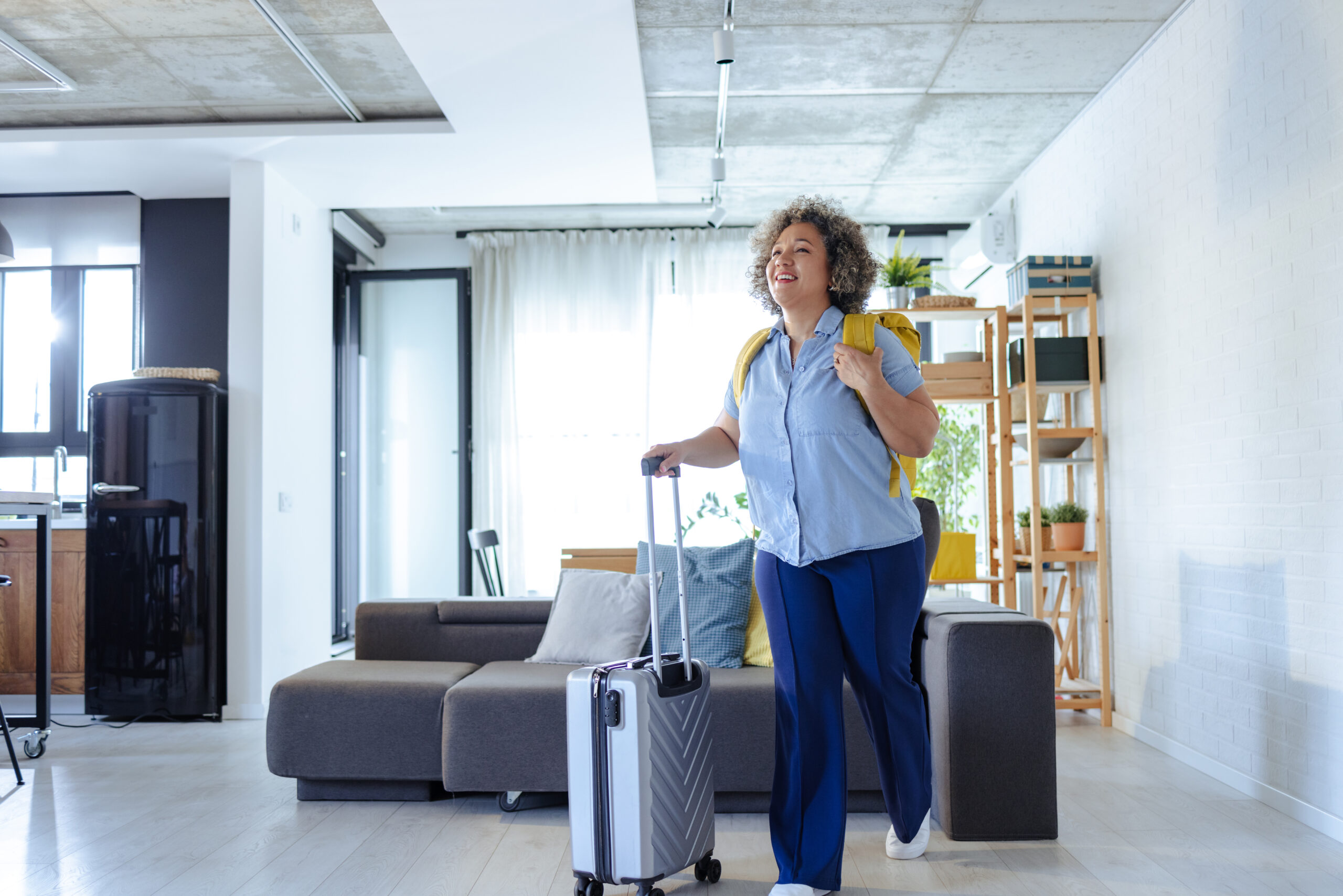 Mature woman with suitcases and a backpack leaves the house and sets out on a journey