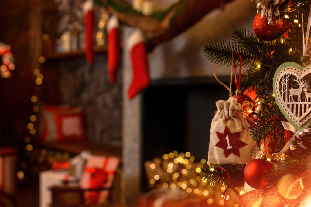 Advent calendar in the form of an eco bag hangs on the Christmas tree against the background of the Christmas room with a fireplace and Santa's boots Christmas background Advent calendar