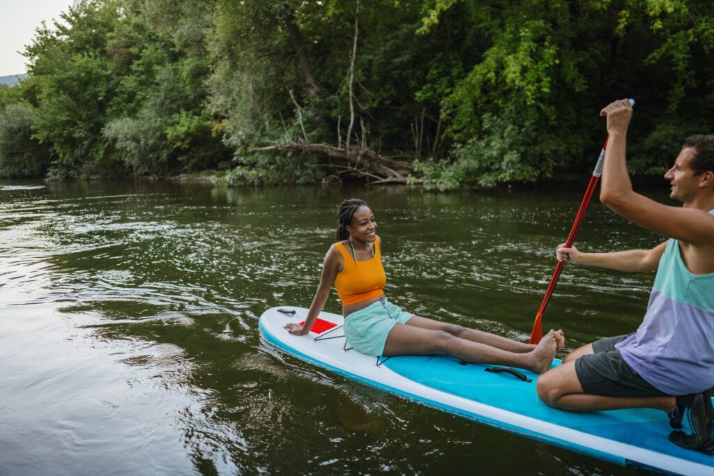 Multiracial couple riding a SUP paddleboard together