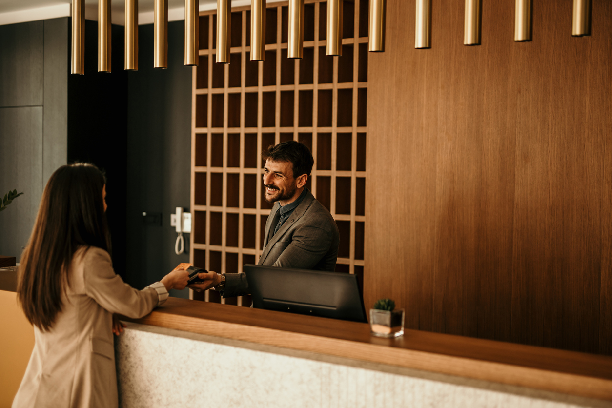 Smiling receptionist behind the hotel counter attending to a female guest The concierge gives the documents to hotel guest